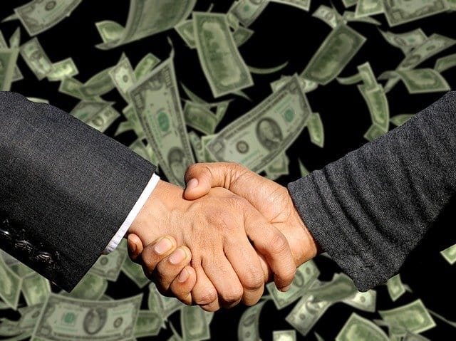 2 businessman hands shake with dollar background