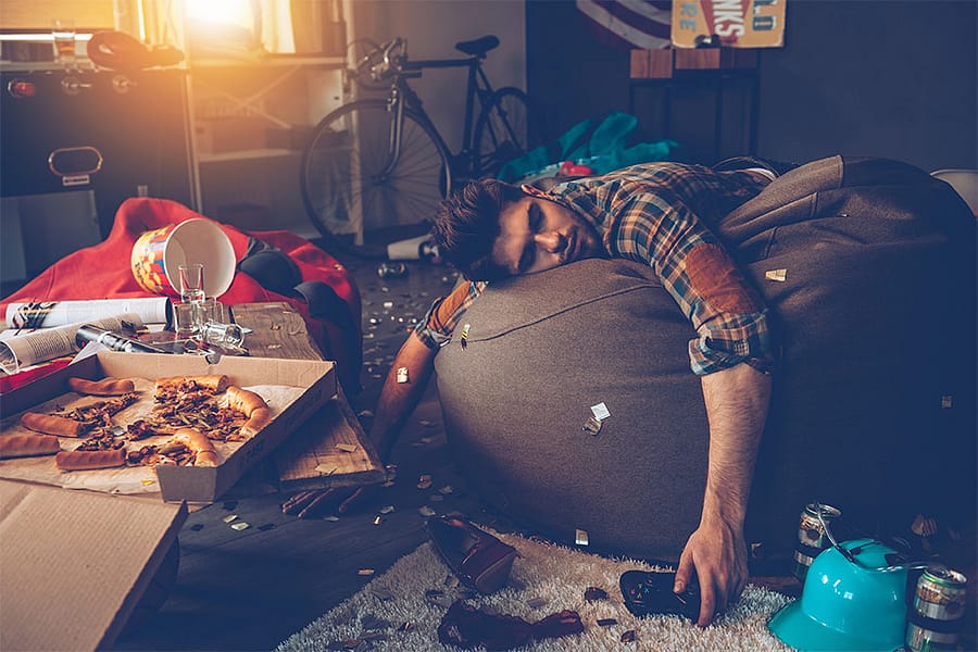 A man sleeping on a bean bag chair in a messy room