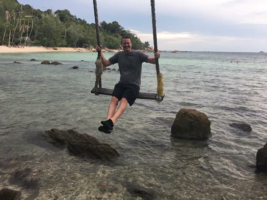 a guy on a huge swing by the ocean
