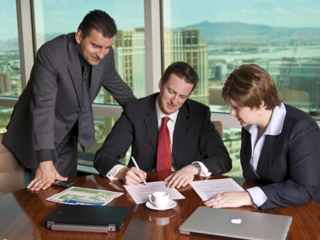three employees discussing signing papers